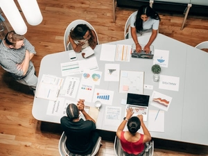 Group of people sitting on a round table with papers and laptop discussing seo