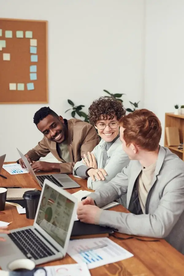 Three colleagues sitting on a table with laptop discussing about work