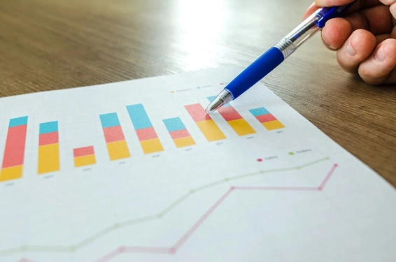 A hand holding a pen pointing on a colorful chart that represent good result